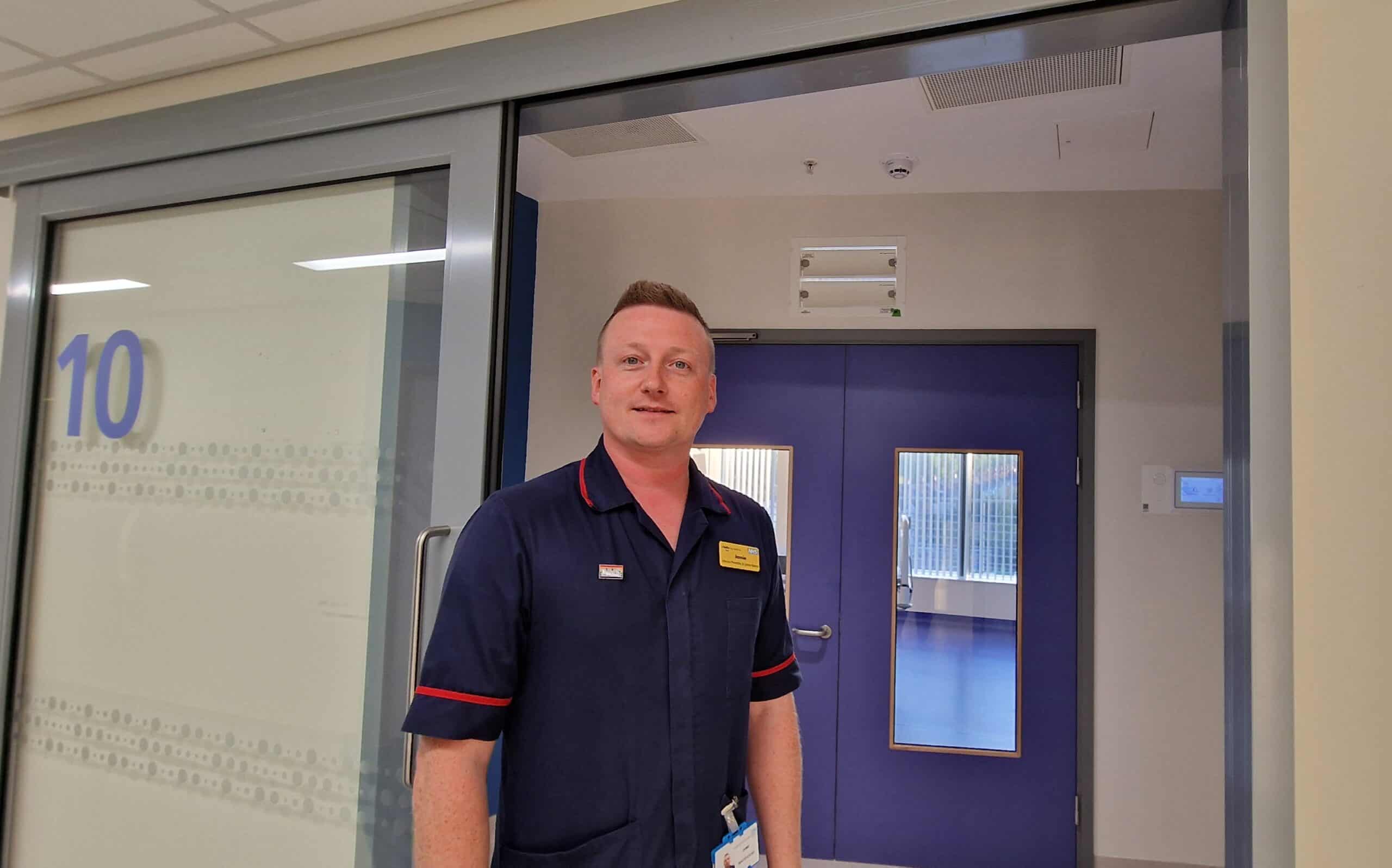 This shows a photograph of Jamie and infection control matron standing in front of an isolation room.