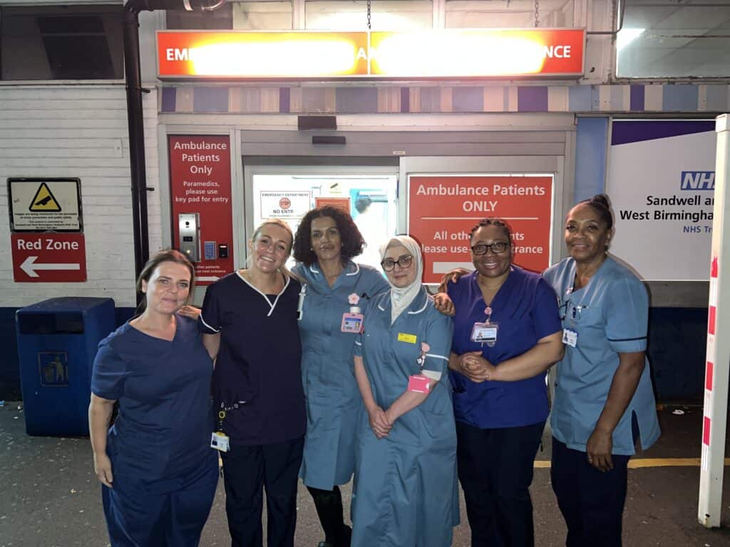 Six nurses and healthcare assistants are lined up.