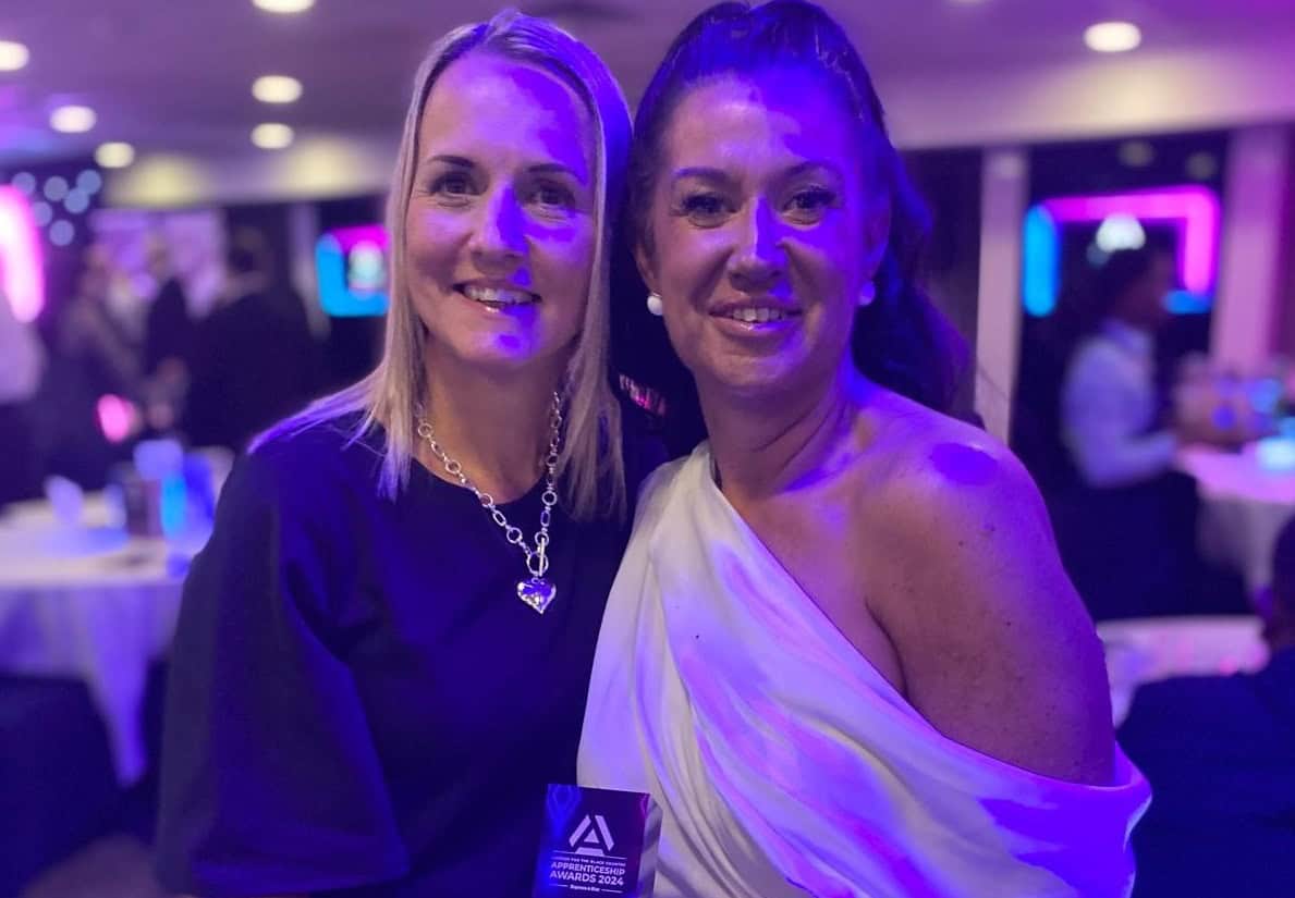 Two women standing next to each other. One lady is holding an award.