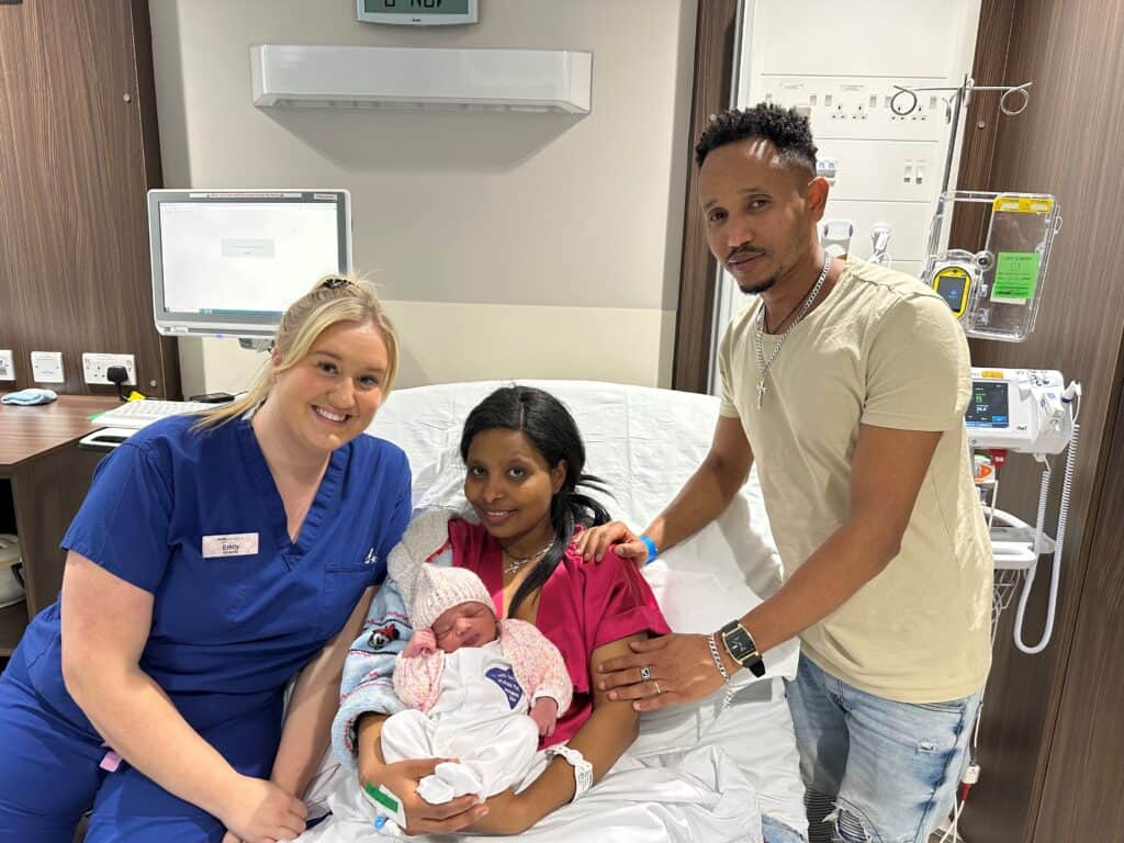 A photo of a midwife with mother, father and newborn baby.