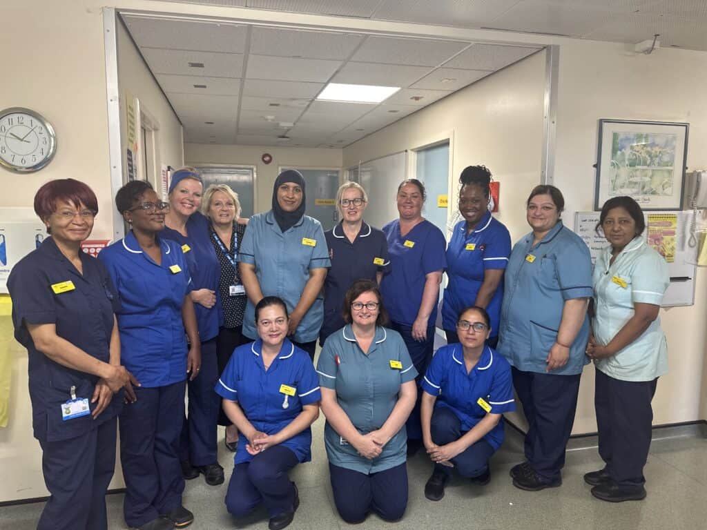 This shows a group of clinical staff of around 13 standing and kneeling in a corridor.